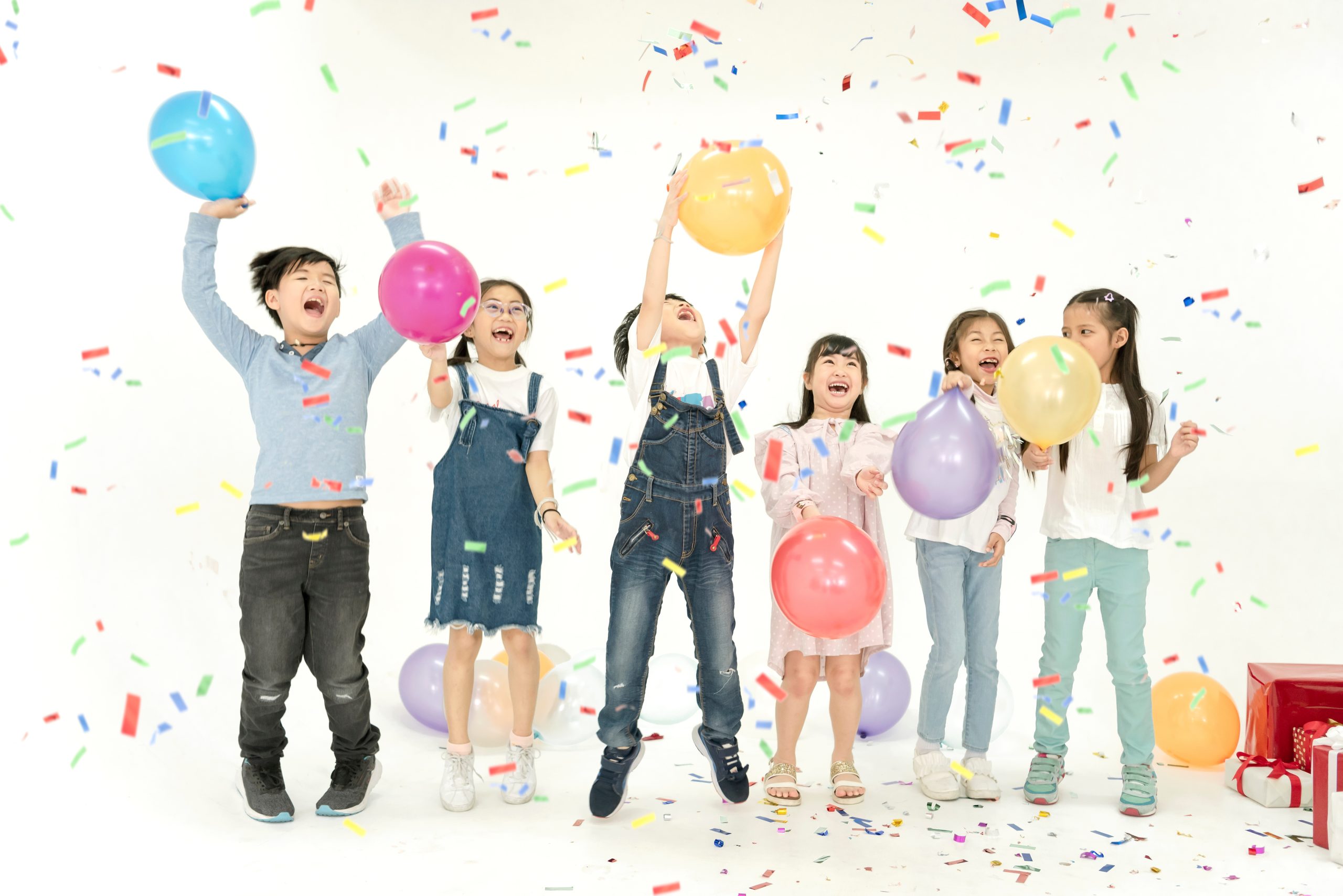 Group of Kids celebrating with balloons and confetti